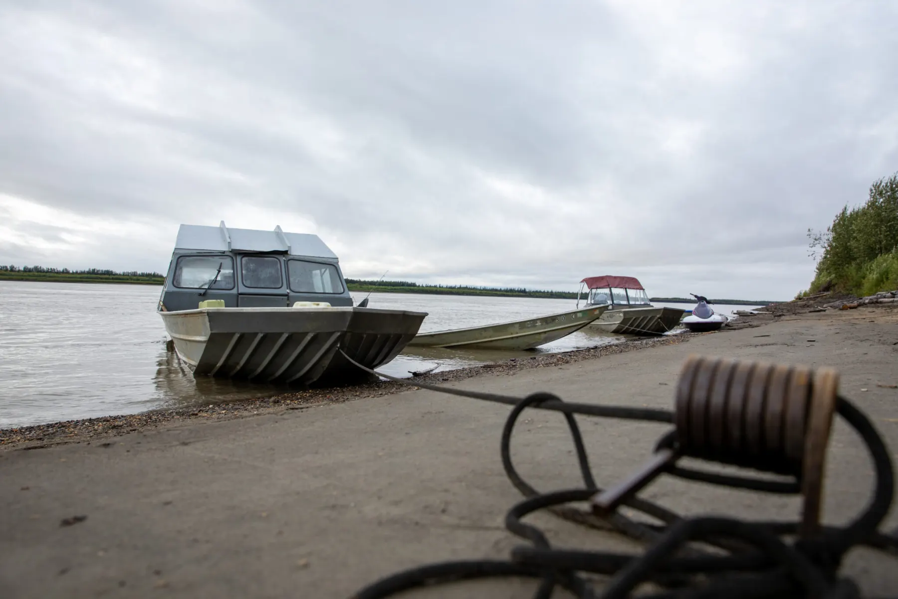 Skiffs pulled up on a gravel riverbank in an Alaska village